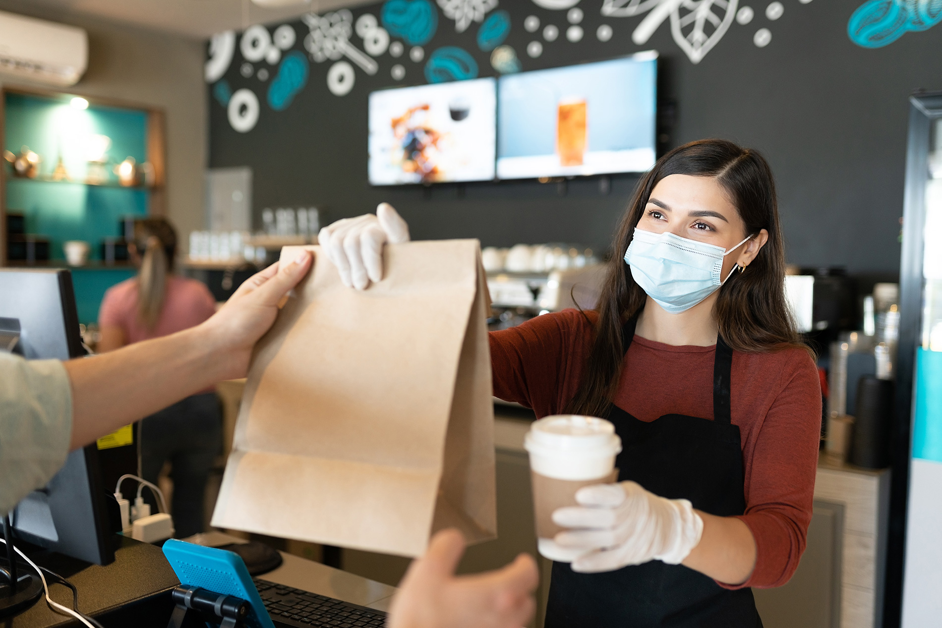 youth with mask handing purchases to client